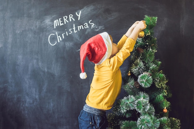 O menino escreveu uma inscrição Feliz Natal. Árvore de Natal. Criança de Natal e feriado de ano novo