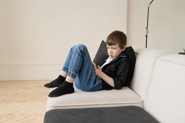 O menino está brincando com o telefone, o problema da tecnologia e das crianças modernas.