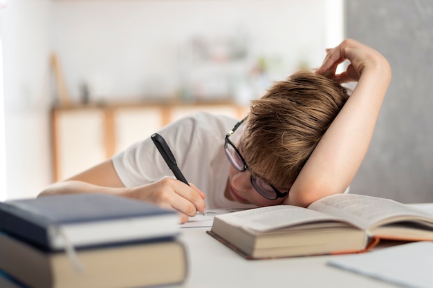 O menino está cansado ao fazer sua lição de casa. Educação escolar em casa. A criança adormeceu enquanto estudava.