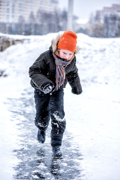 O menino está correndo no gelo na neve