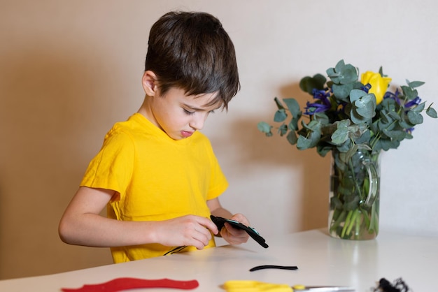 o menino está fazendo bordado Costurando um brinquedo macio de mãos de feltro closeup Passatempo em casa