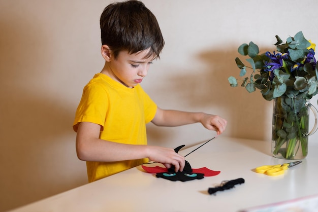 o menino está fazendo bordado Costurando um brinquedo macio de mãos de feltro closeup Passatempo em casa