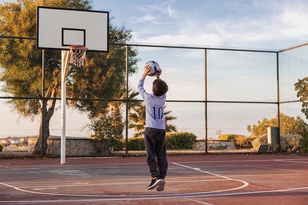 O menino está jogando basquete na rua