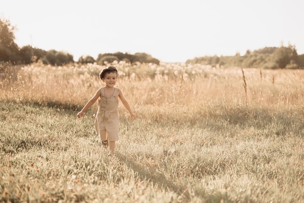 O menino está se divertindo e correndo ativamente no campo Um menino alegre e sinceramente alegre Infância no campo
