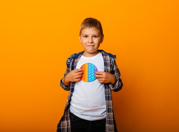 O menino está segurando brinquedos sensoriais nas mãos. empurre o jogo pop-it. menino feliz com pop-lo