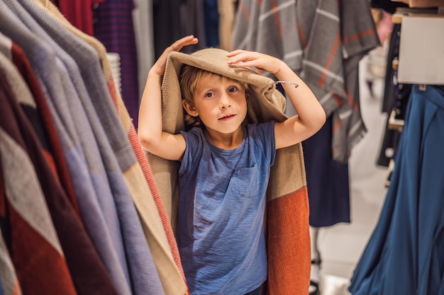 O menino experimenta roupas na loja de roupas infantis