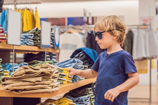 O menino experimenta roupas na loja de roupas infantis.