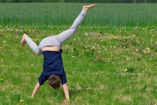 Foto o menino faz uma roda acrobática na grama