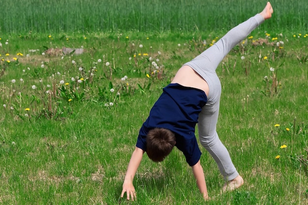 O menino faz uma roda acrobática na grama