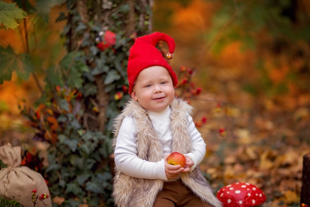 O menino gnomo feliz da floresta das fadas brinca e caminha na floresta, coleta e come maçãs deliciosas