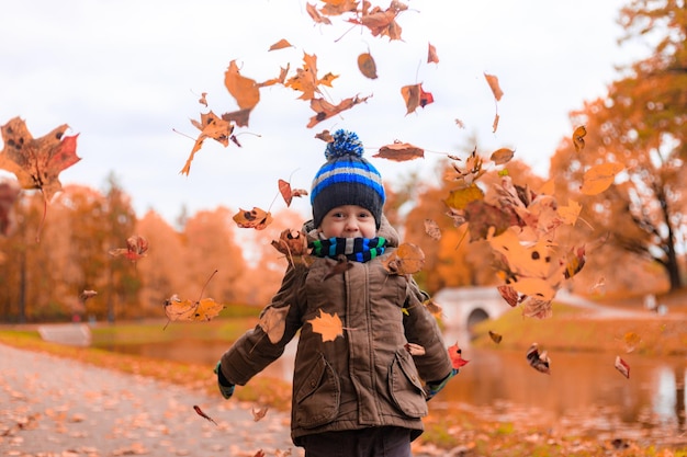 O menino joga folhas de outono Artigo de outono Uma criança feliz Outono