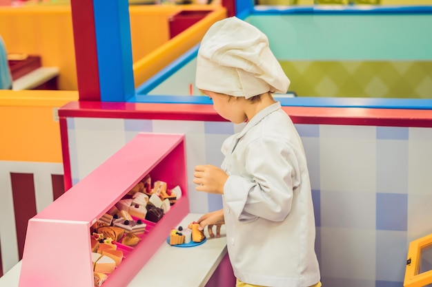 O menino joga o jogo como se fosse um cozinheiro ou um padeiro na cozinha de uma criança