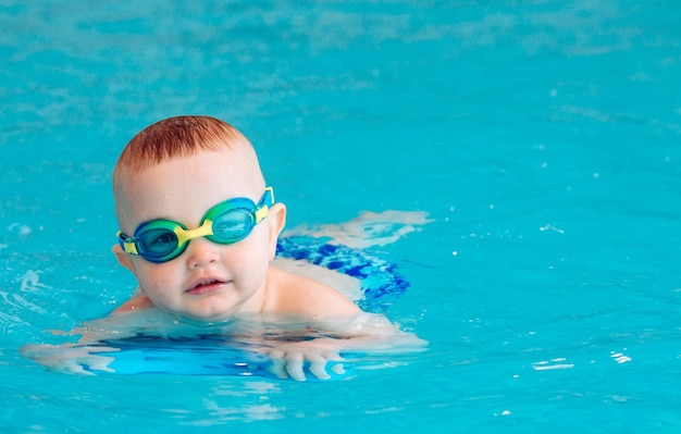 O menino nada independente na piscina.