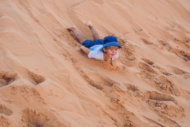 O menino no deserto vermelho ao amanhecer. Viajar com o conceito de crianças.