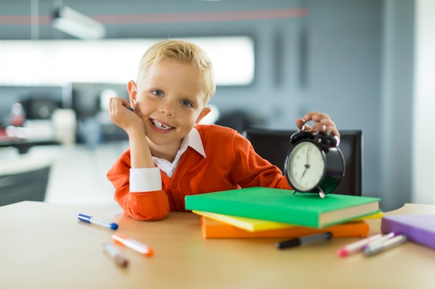 O menino novo senta-se na mesa no escritório