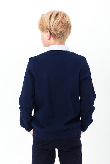 O menino posa em um uniforme escolar uma camisa e uma jaqueta em um fundo branco Um adolescente fica de costas para a câmera Foto vertical