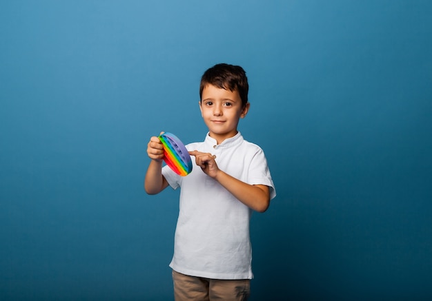 O menino tem brinquedos de bater palmas nas mãos. Jogo push. Garoto feliz com estourá-lo.