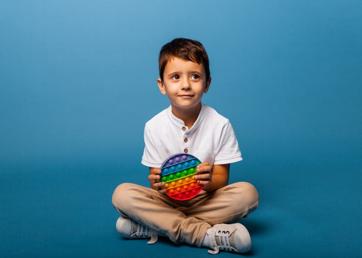 Foto o menino tem brinquedos de bater palmas nas mãos. jogo push. garoto feliz com estourá-lo.