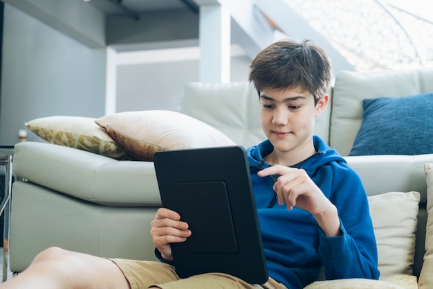 O menino usando tablet para comunicação online em casa