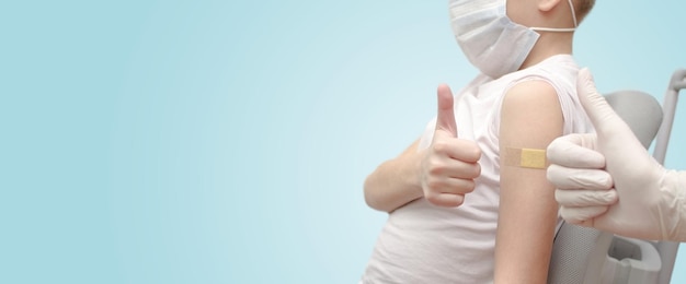 O menino vacinado em uma máscara junto com o médico mostra um polegar para cima
