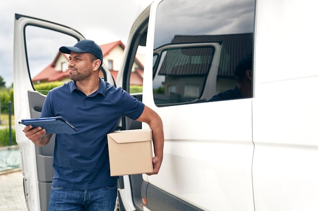 O mensageiro do homem com a encomenda olha ao redor de um carro de entrega