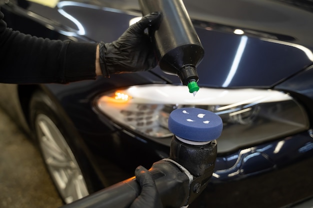 Foto o mestre de detalhamento aplica pasta de polimento automotivo ao polidor.