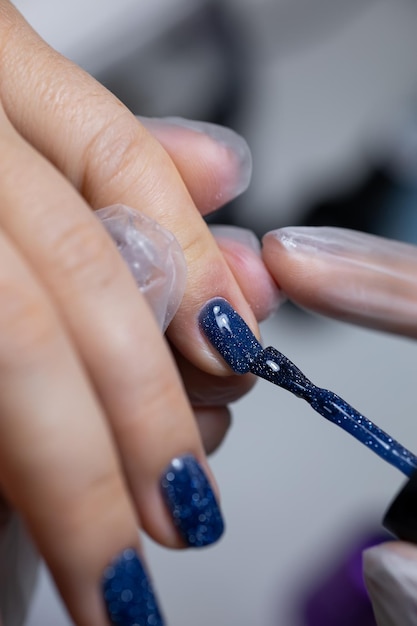 O mestre de manicure realiza o procedimento de aplicar um belo esmalte de gel na unha