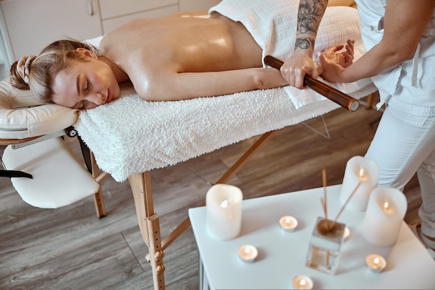 O mestre de massagem profissional confiante está fazendo procedimentos para uma mulher caucasiana em estilo minimalista moderno
