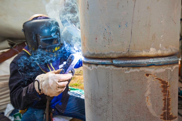 O metal do trabalhador masculino de soldagem faz parte da construção do encanamento do bocal de máquinas