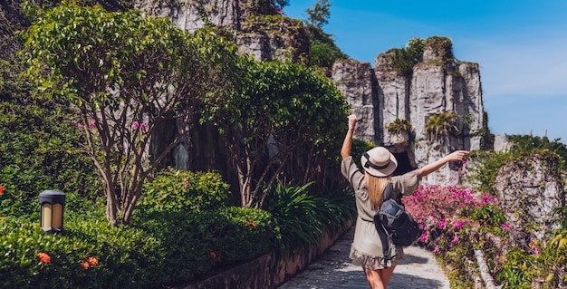 O mochileiro louro bonito da mulher anda e admira paisagens tropicais no hotel da ilha do paraíso em Sanya, China.