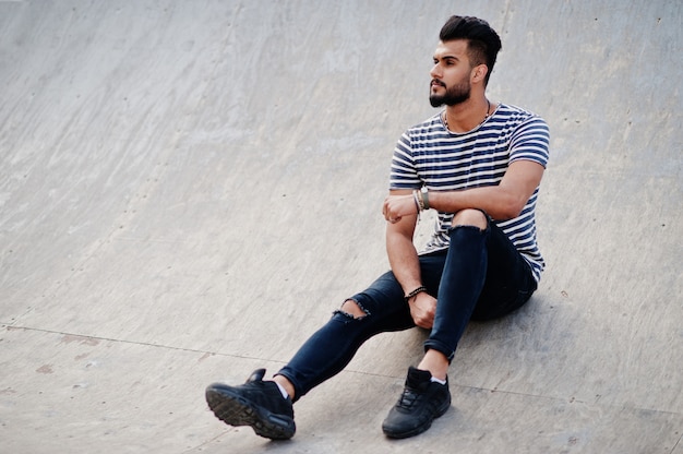 O modelo árabe alto considerável do homem da barba na camisa descascada levantou exterior. Cara árabe na moda.