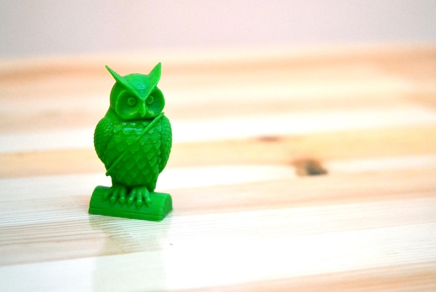 O modelo impresso em um objeto de impressora d na forma de uma coruja de cor verde está na mesa