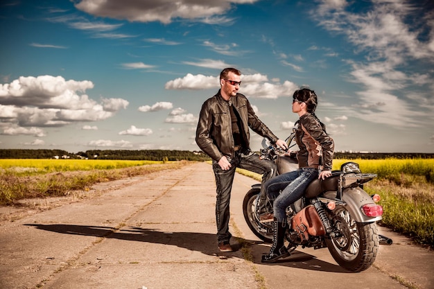O motociclista e a garota ficam na estrada e olham para longe
