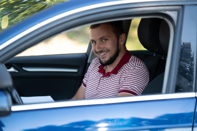 O motorista do instrutor do homem está no carro e sorrindo