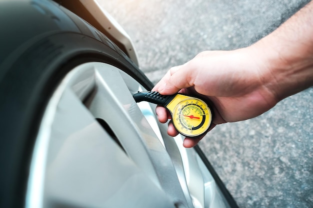 O motorista está medindo a pressão dos pneus com um conceito de serviço de manutenção automática de medidor de pressão de pneu padrão