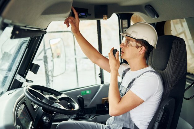 O motorista está no trabalho O homem de uniforme profissional está no poço de empréstimo durante o dia