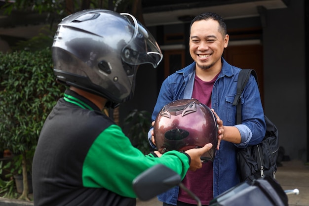 O mototaxista on-line está dando capacete ao cliente antes do passeio