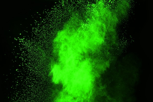 O movimento da explosão de poeira abstrata congelou o verde no fundo preto.