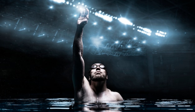 O nadador na piscina levanta as mãos.