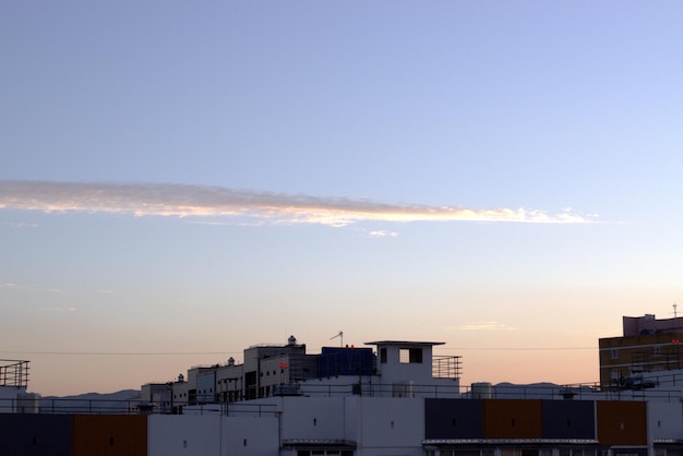 O nascer do sol ilumina uma nuvem engraçada e os telhados de novos edifícios urbanos um banner um protetor de tela