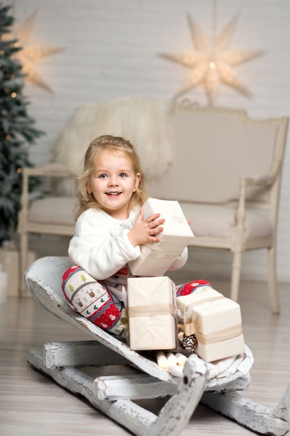 O natal já está aqui. menina de trenó com caixa de presente de natal. a menina bonito pequena recebeu presentes de época natalícia. garoto segura a caixa de presente enquanto andar de trenó. celebrar o natal. atividade de inverno