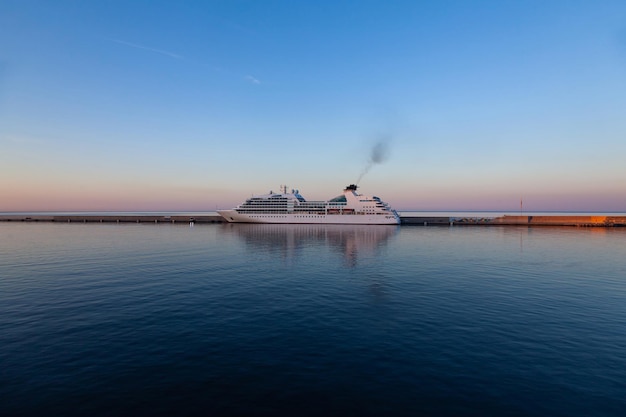 O navio de cruzeiro sai do cais e sai para o mar ao pôr do sol