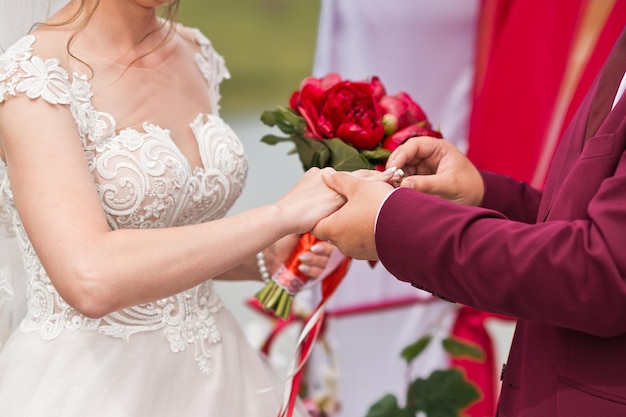 O noivo coloca um anel de noivado no dedo da noiva em um fundo verde