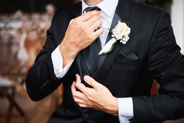 Foto o noivo de elegnat no terno à moda preto que põe sobre um laço na manhã antes do casamento.