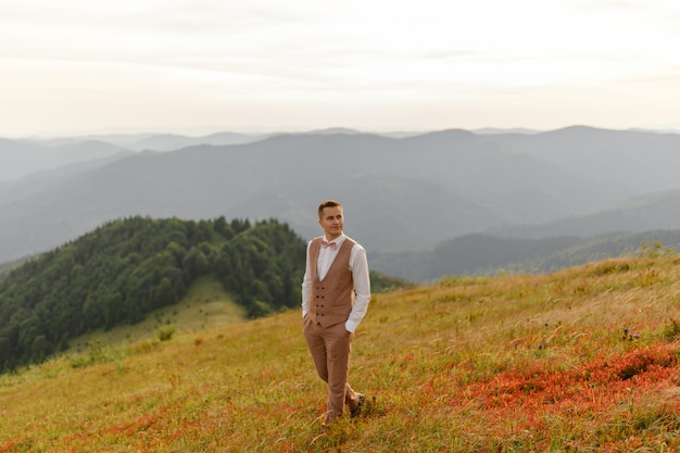 O noivo está andando sozinho no fundo das montanhas de outono.
