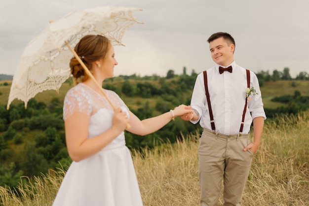 O noivo segura a noiva pela mão no casamento contra a bela paisagem