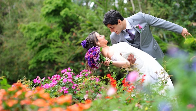 O noivo segurando a noiva enquanto está de pé no jardim