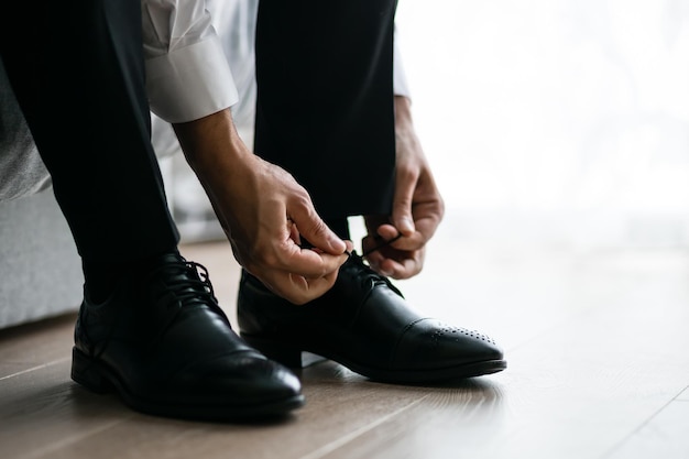 O noivo usa sapatos pela manhã antes da cerimônia de casamento Estilo masculino