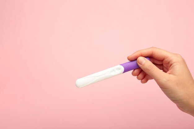 O novo teste de gravidez em fundo rosa conceito de cuidados de saúde