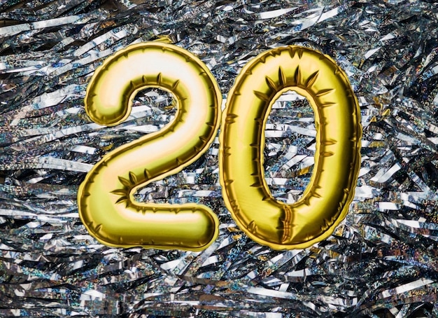 Foto o número 20 em um fundo prateado data do feriado a figura é feita de folha de ourovinte anos de aniversário
